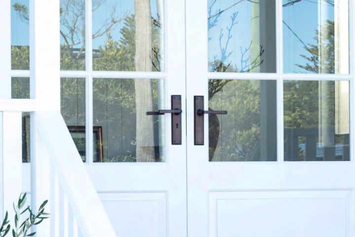 Classic French doors with divided glass panels, featuring a stylish brass handle. From handles, locks, french door fasteners, and everything in between, learn how to select the best French Door Hardware with Paddington Hardware.