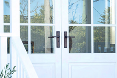 Classic French doors with divided glass panels, featuring a stylish brass handle. From handles, locks, french door fasteners, and everything in between, learn how to select the best French Door Hardware with Paddington Hardware.